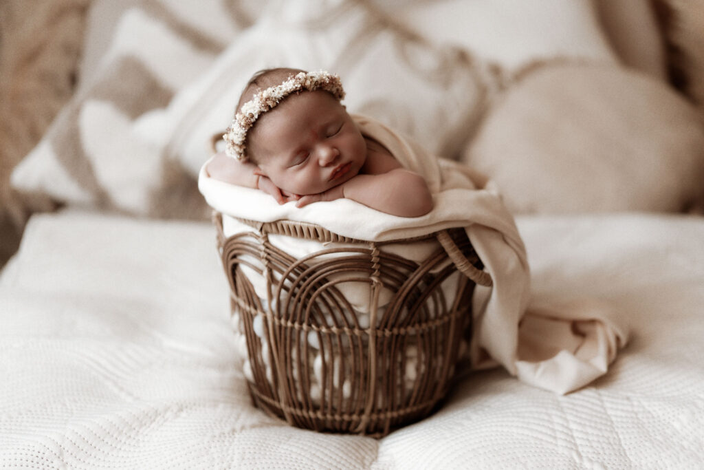 Schlafendes Baby mit Blumenband in einem kleinen Körbchen im Studio